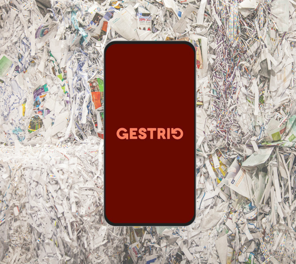 Un cellulaire présentant le logo de Gestrio devant un amas de papiers journaux